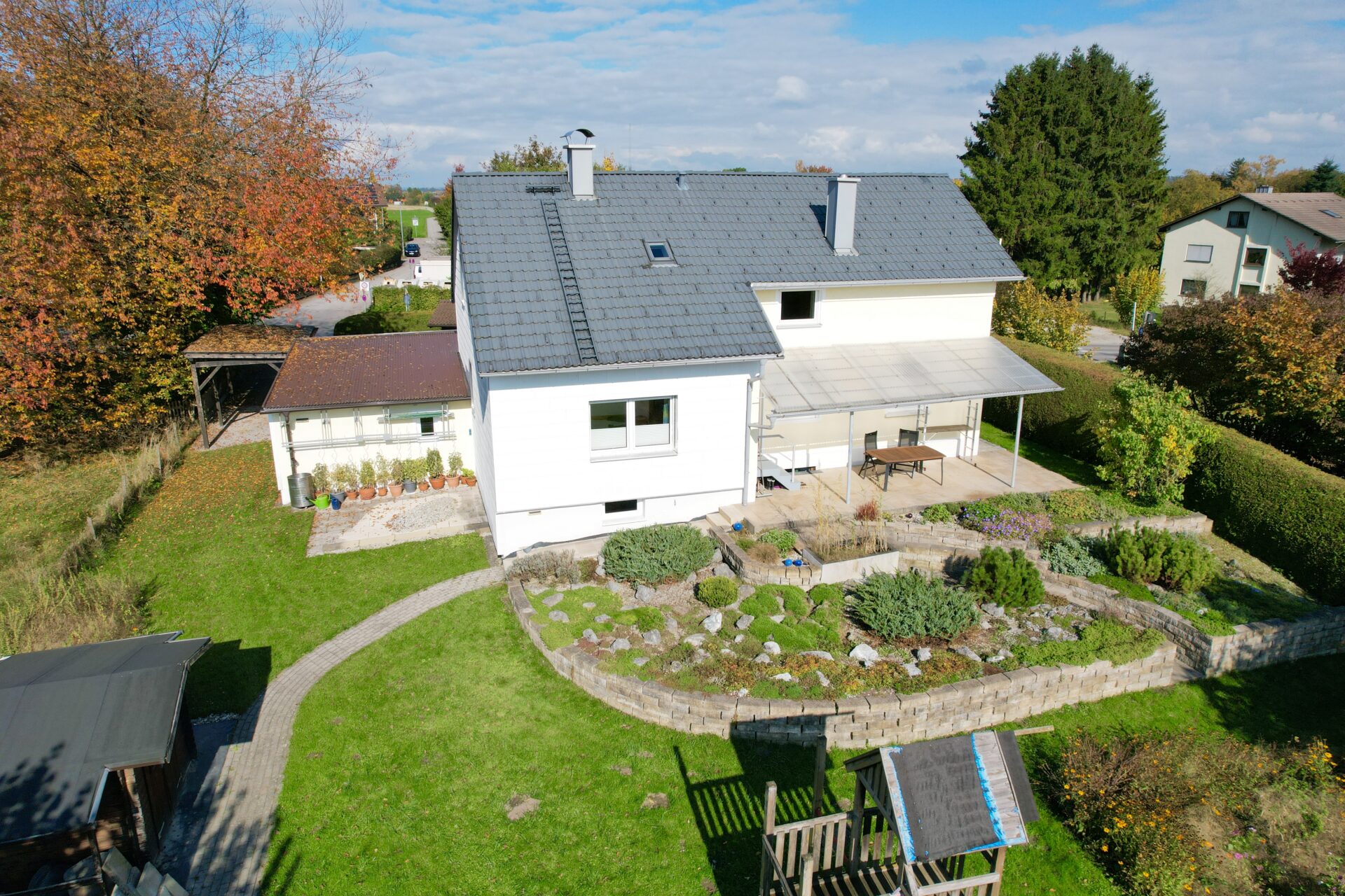Drohnen- Aufnahme von einer sonnigen Hausfassade mit Terrasse und Garten